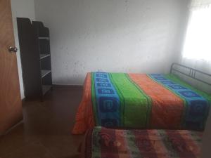 - une chambre avec un lit et une couverture colorée dans l'établissement Quiero finquear, à Manizales