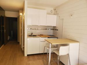 a kitchen with white cabinets and a wooden table at Studio cosy Edelweiss in Luchon