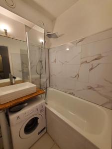a bathroom with a sink and a washing machine and a tub at Studio cosy Edelweiss in Luchon +13 photos