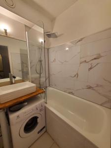 a bathroom with a sink and a washing machine and a tub at Studio hyper centre in Luchon