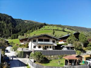 a house with a green hill in the background at Appartement Josefine in Bramberg am Wildkogel
