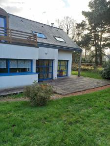 une maison avec une terrasse en bois dans la cour dans l'établissement Magnifique villa de 4 chambres 140 m2 à 1,5 km de la mer, à Pleumeur-Bodou