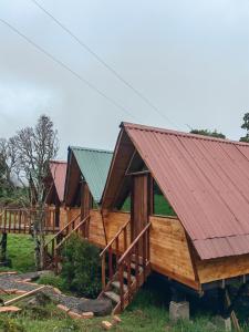 a row of wooden homes with a red roof at Cabañas del bosque in Choachí