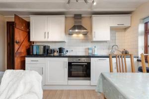 a kitchen with white cabinets and a stove top oven at Cowslip Cottage Serenity with Jacuzzi in Saundersfoot