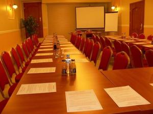 een lange tafel in een vergaderzaal met rode stoelen bij Hotel Jabłoński in Dorotowo