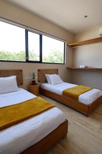 two beds in a room with two large windows at Akbal Tulum in Tulum