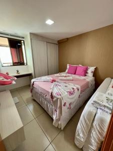 um quarto com 2 camas com lençóis cor-de-rosa e brancos em Apartamento a beira mar com piscina estilo resort em Cabedelo