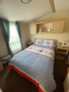 a small bedroom with a bed and a window at Serendipity Caravan Hire in Chapel Saint Leonards