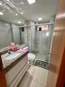 La salle de bains est pourvue de toilettes, d'un lavabo et d'une douche. dans l'établissement Apartamento a beira mar com piscina estilo resort, à Cabedelo