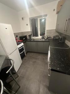 La cuisine est équipée d'un réfrigérateur blanc et d'un évier. dans l'établissement Sutton Coldfield Apartment, à Birmingham