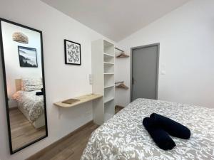 een witte slaapkamer met een bed en een spiegel bij La Terrasse étoilée in Montbrison