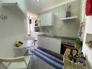 uma cozinha com armários brancos, uma mesa e um fogão em EVD-RENTALS OLIVAL BASTOS em Lisboa
