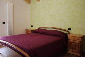 1 dormitorio con 1 cama con manta morada en Appartamento vacanze Riccardo ed Ester, en Ronzo Chienis