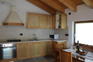 una cocina con armarios de madera y una mesa con fregadero en Appartamento vacanze Riccardo ed Ester en Ronzo Chienis