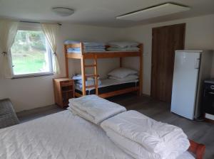 a bedroom with two bunk beds and a refrigerator at Lesní chaty "Hogo Fogo" in Kytlice