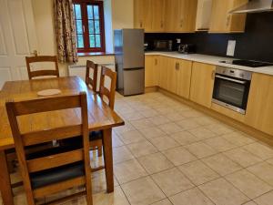 a kitchen with a wooden table and a refrigerator at Peregrine Stable Cottage in Llandovery