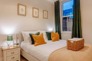 a bedroom with a bed with orange and green pillows at Mayfield - Central Harrogate Apartment - Ground Floor in Harrogate