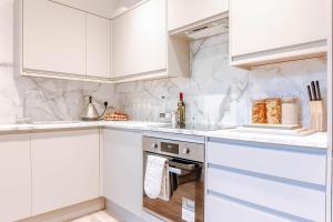 a white kitchen with white cabinets and a dishwasher at Mayfield - Central Harrogate Apartment - Ground Floor in Harrogate
