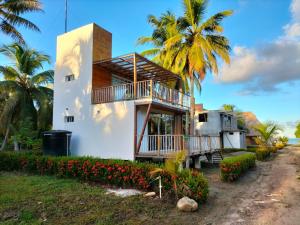 a house with a balcony and palm trees at cabañas Brisas y Perla by AMAUNA in Moñitos
