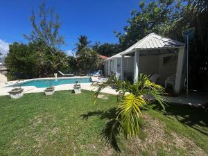 a small house next to a swimming pool at Rafeen villa- Historic villa with pool in Bridgetown