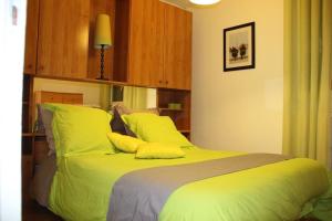 a bedroom with a green bed with yellow pillows at Chelles - Paris - Disneyland Marne la vallée in Chelles