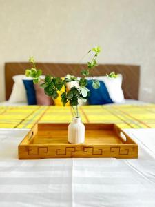 ein Holztablett mit einer Blumenvase auf dem Bett in der Unterkunft Евродвушка вблизи MegaSilkWay & EXPO in Prigorodnyy