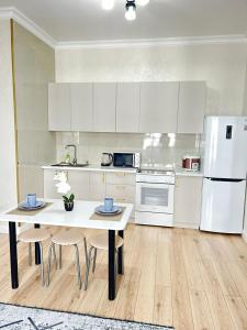 eine Küche mit einem Tisch und einem weißen Kühlschrank in der Unterkunft Евродвушка вблизи MegaSilkWay & EXPO in Prigorodnyy