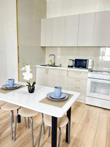 eine Küche mit einem weißen Tisch, Stühlen und einem Herd in der Unterkunft Евродвушка вблизи MegaSilkWay & EXPO in Prigorodnyy