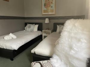 The Sun Inn في هيكسهام: غرفة نوم بسريرين بها شراشف بيضاء ومصباح