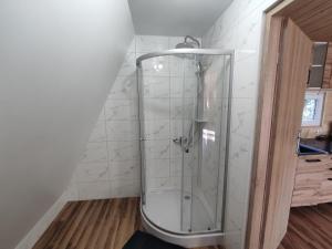 La salle de bains est pourvue d'une douche et de carrelage blanc. dans l'établissement Domki Bory Tucholskie - Kurs na wypoczynek, à Osieczna