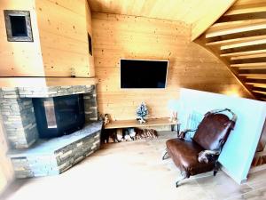 a living room with a fireplace and a chair at Chalet Neuf, Morgins in Morgins
