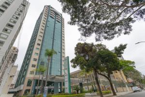 a tall building with palm trees in front of it at Green Place Ibirapuera in Sao Paulo