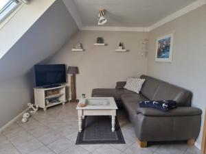 ein Wohnzimmer mit einem Sofa und einem TV in der Unterkunft Ferienwohnung Petersen in Nordstrand