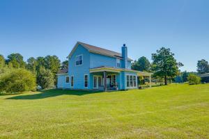 a blue house on a large grass field at Peaceful Haynesville Vacation Rental with Yard! 