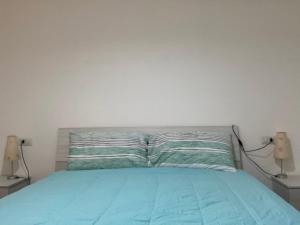 a bedroom with a bed with blue sheets and two lamps at front streat 5 in Sassari