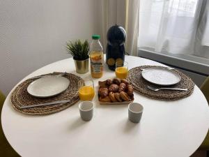 a white table with two plates and two glasses of orange juice at Le Cordelier-Proche marché central et vieux port-wifi haut débit- in La Rochelle