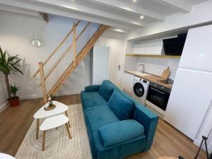 a living room with a blue couch and a kitchen at Le Cordelier-Proche marché central et vieux port-wifi haut débit-Netflix in La Rochelle