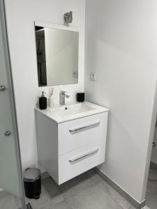 ein weißes Badezimmer mit einem Waschbecken und einem Spiegel in der Unterkunft Résidence du Temple in Martigues