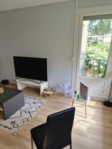 uma sala de estar com uma grande televisão de ecrã plano em Ian'Éliel Appart em Compiègne