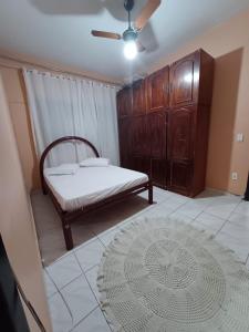 1 dormitorio con 1 cama y armario de madera en Casa Arraial do Cabo, en Arraial do Cabo