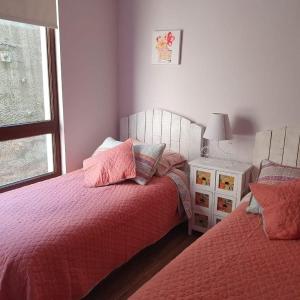 Un dormitorio con dos camas y una ventana. en Departamento Pucón - Salida directa al Lago Villarrica, en Pucón
