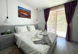 a bedroom with a bed and a large window at Mountain River Loft in Buşteni