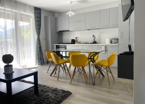 a kitchen with a dining table and yellow chairs at Mountain River Loft in Buşteni