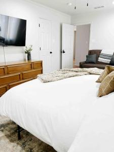 um quarto com uma grande cama branca e uma televisão em NEW Magnolia Mansion-4400sqft Hot Tub & 2 Game Rms em Lubbock