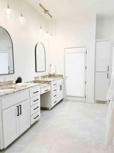 Baño blanco con 2 lavabos y 2 espejos en NEW Magnolia Mansion-4400sqft Hot Tub & 2 Game Rms, en Lubbock