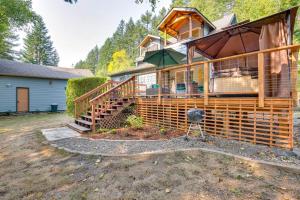a large house with a deck and a grill at Historic Mapleton Cottage with River Views and Hot Tub in Mapleton