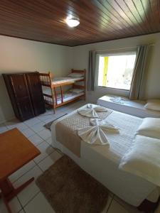a bedroom with two beds and a window at Pousada Vô Lica com piscina in Penha