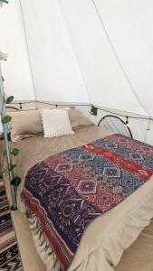 a bed in a tent with a quilt on it at Killary Lodge in Cachanlo de Sidcay