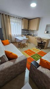 a living room with two beds and a table and a kitchen at Aliaj's Guest House in Berat