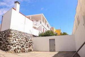 un edificio bianco con una porta e un muro di Maruca (D): En familia. a Breña Baja